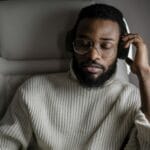 Mężczyzna w swetrze słucha muzyki w słuchawkach na pokładzie samolotu