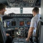 Dwóch pilotów koncentruje się na przyrządach w kokpicie samolotu