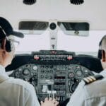 Dwóch pilotów obsługuje przyrządy w kokpicie samolotu