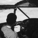 Pilot w kokpicie samolotu widziany z tyłu, czarno-białe ujęcie