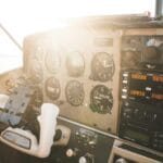 Pilot w słonecznym kokpicie przy panelu nawigacji samolotu