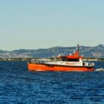 Pomarańczowa łódź pilotowa płynąca wzdłuż wybrzeża przy bezchmurnym niebie