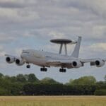 Samolot AWACS ląduje na pasie startowym pod zachmurzonym niebem