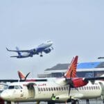 Samolot startuje z pasa, obok stoją maszyny na płycie lotniska