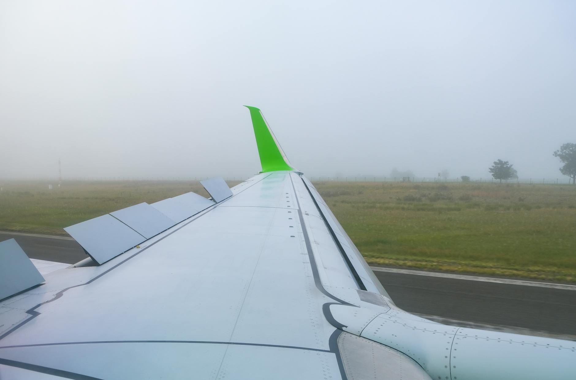 Skrzydło samolotu pasażerskiego w gęstej mgle podczas startu