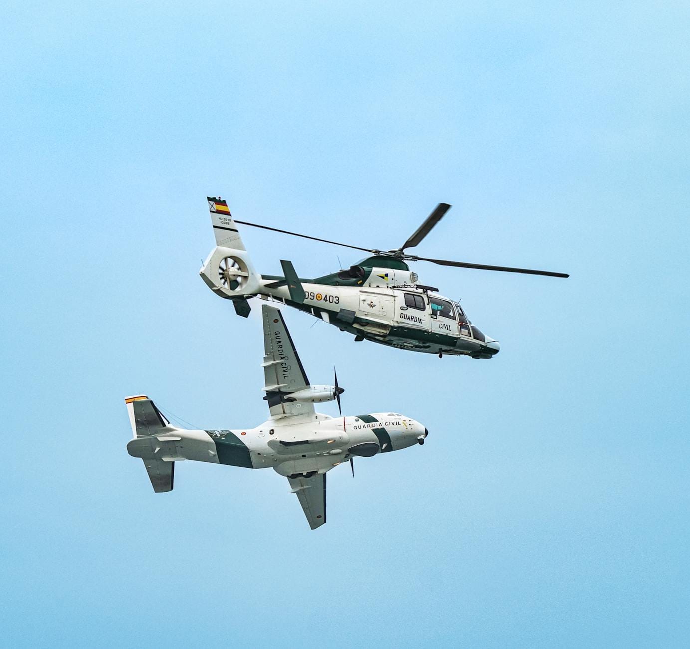 Wojskowy śmigłowiec i samolot wykonujące manewr w powietrzu