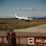 Mały samolot na trawiastym lądowisku obok znaku ostrzegawczego