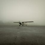 Mały samolot stoi samotnie na zamglonym pasie startowym