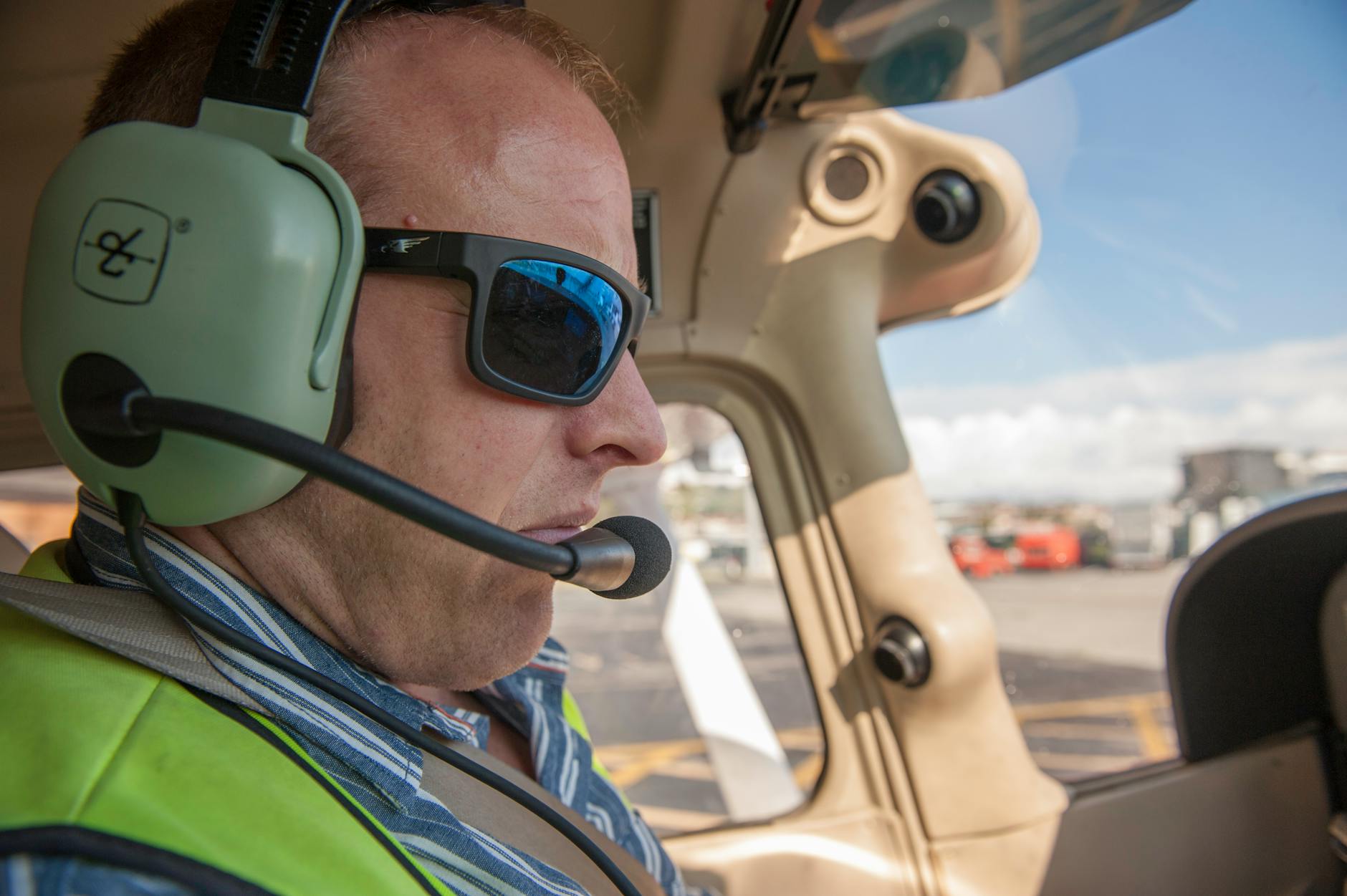 Pilot w okularach przeciwsłonecznych słuchający ATC w kokpicie samolotu