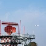 Samolot przy radarowej wieży na tle błękitnego nieba