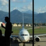 Sylwetka pasażera w lotnisku Bergamo z samolotem i górami w tle