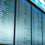 Tablice odlotów i przylotów na ekranach w terminalu lotniska