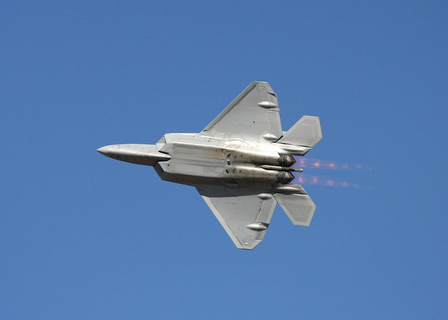 Myśliwiec F-22 Raptor z dopalaczami na tle czystego błękitnego nieba