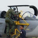 Pilot wojskowy wchodzi do kokpitu myśliwca na pokładzie lotniskowca