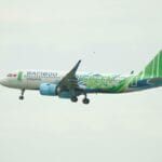 Samolot Bamboo Airways w zielonych barwach leci na tle czystego nieba