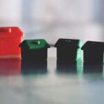 Czerwone i zielone domki z gry Monopoly odbijające się w lśniącej powierzchni