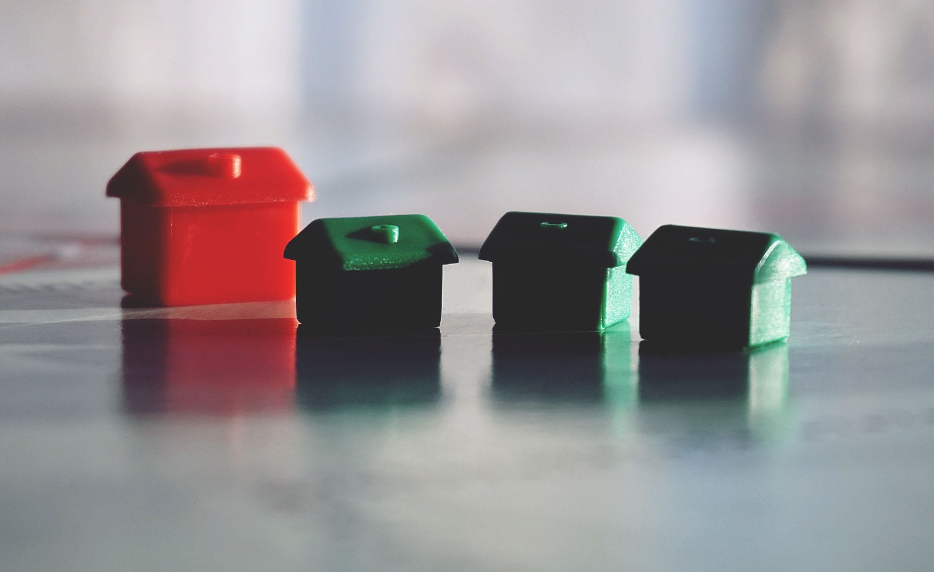 Czerwone i zielone domki z gry Monopoly odbijające się w lśniącej powierzchni