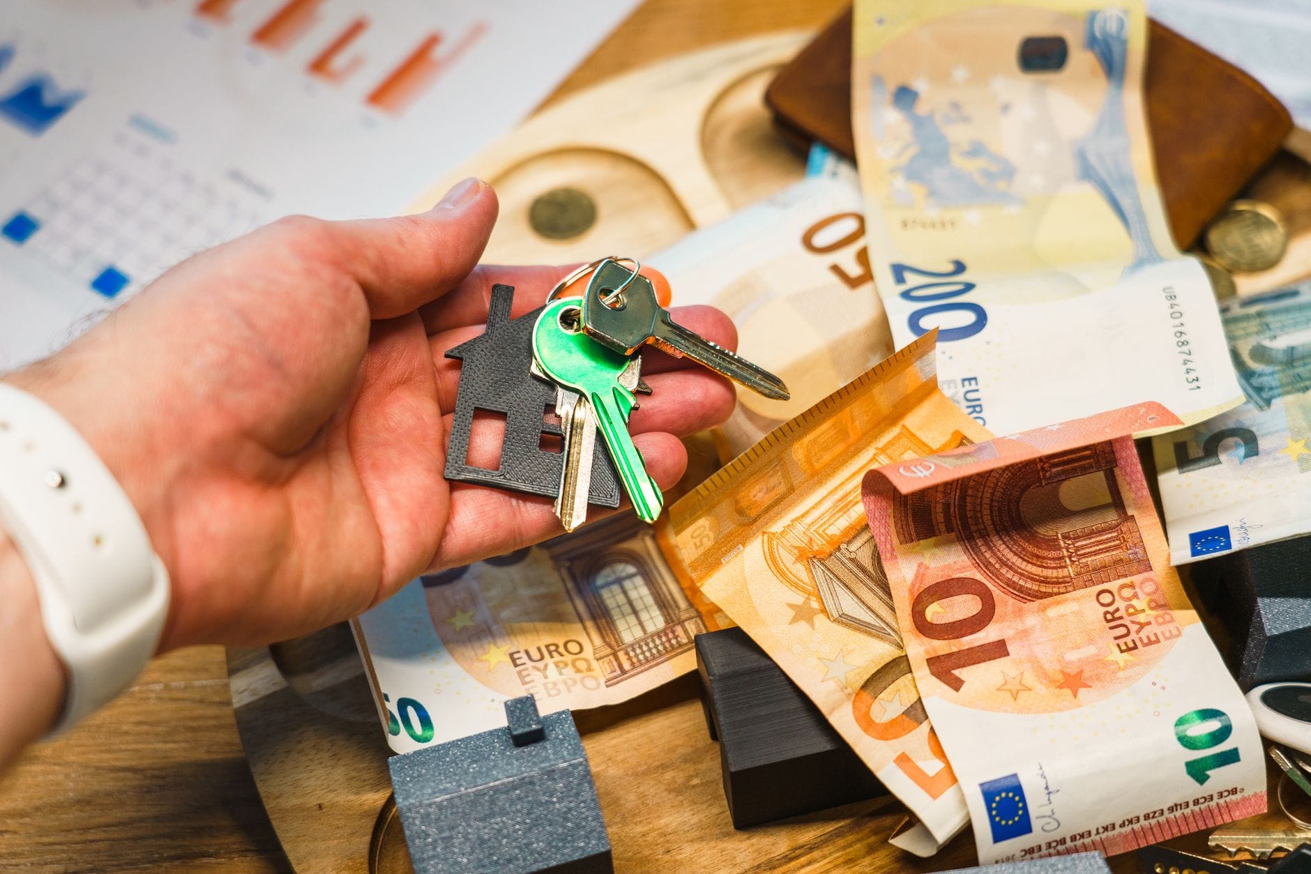 Dłoń trzymająca klucze do domu nad banknotami euro