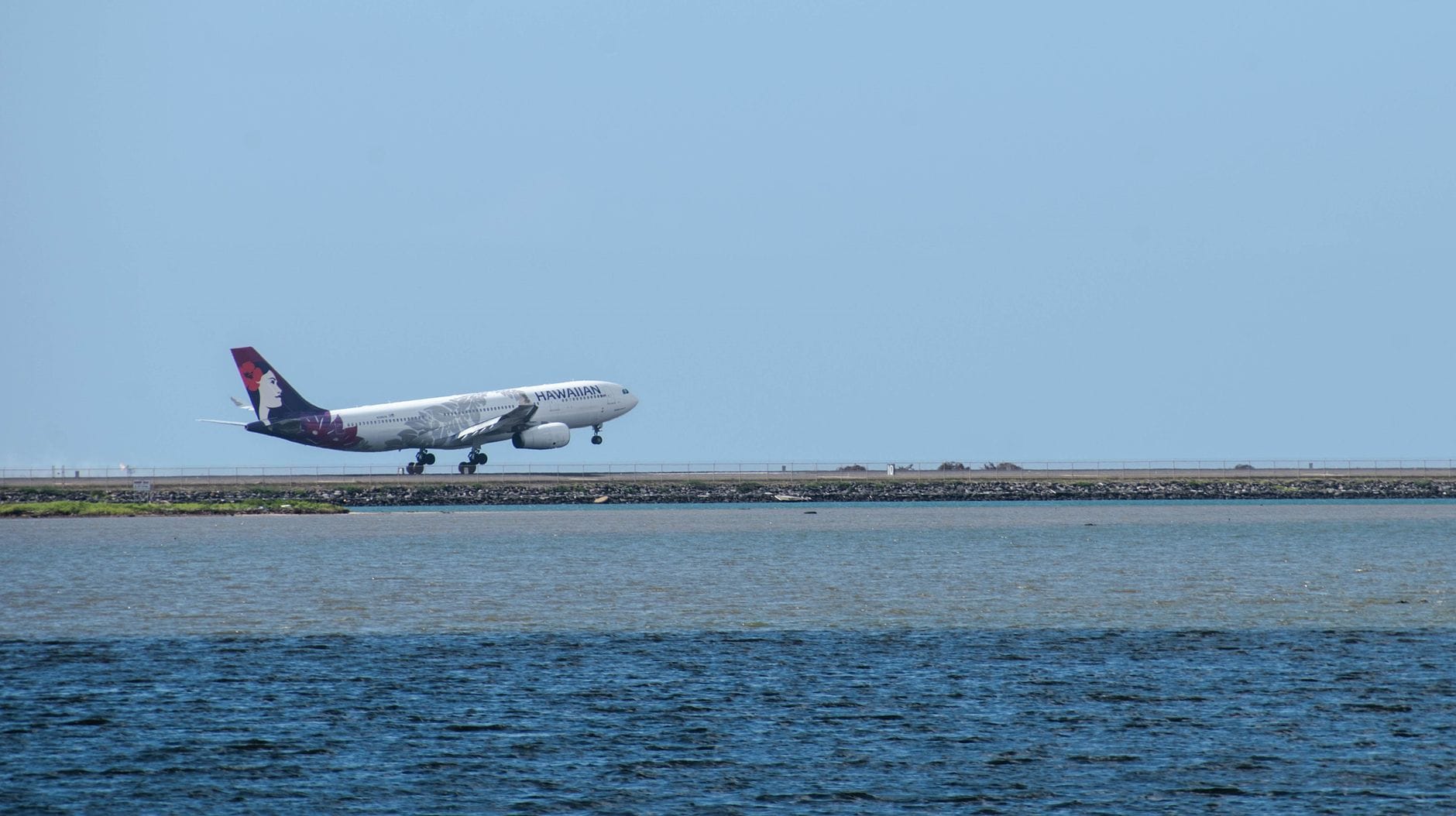 Samolot Hawaiian Airlines startuje z pasa przy oceanie