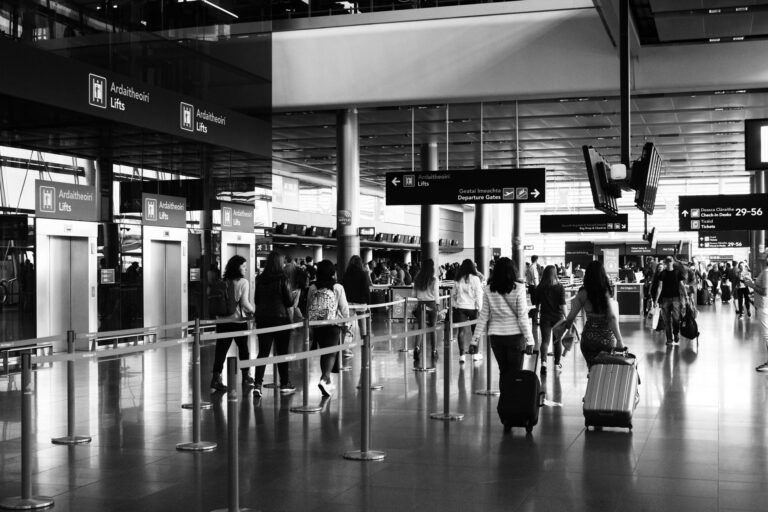 Podróżni z bagażami idący przez zatłoczony terminal lotniska